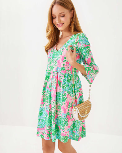 Smiling model in the Lilly Pulitzer Jannie V-Neck 3/4 Sleeve Dress - Multi - Plumes In Bloom with rattan purse 