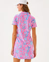 Back view of smiling model in the Lilly Pulitzer Dune Short Sleeve Dress - Rousseau Pink - Barefoot Beachcombers. A hot pink mini dress with short sleeves and a collar, with light blue beach motifs 
