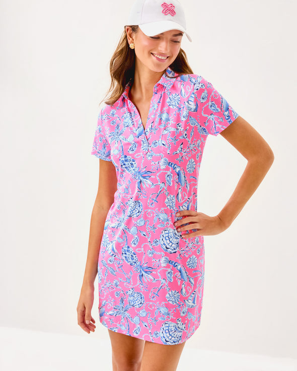 Front view of smiling model in the Lilly Pulitzer Dune Short Sleeve Dress - Rousseau Pink - Barefoot Beachcombers. A hot pink mini dress with short sleeves and a collar, with light blue beach motifs 