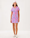 Full view of smiling model in the Lilly Pulitzer Dune Short Sleeve Dress - Rousseau Pink - Barefoot Beachcombers. A hot pink mini dress with short sleeves and a collar, with light blue beach motifs 