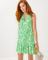Model in the Lilly Pulitzer Riegan Dress - Fauna Green. A sleeveless mini dress with a mock neck and ruffle at the bottom hem, in a green floral pattern 