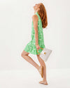 Side view of the Model in the Lilly Pulitzer Riegan Dress - Fauna Green. A sleeveless mini dress with a mock neck and ruffle at the bottom hem, in a green floral pattern 