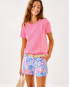 Smiling model in the Lilly Pulitzer Callahan Stretch Short - Elephant Splash. Light blue shorts with pink, blue, yellow, and purple details 