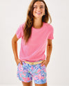 Smiling model in the Lilly Pulitzer Callahan Stretch Short - Elephant Splash. Light blue shorts with pink, blue, yellow, and purple details 