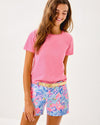 Smiling model in the Lilly Pulitzer Callahan Stretch Short - Elephant Splash. Light blue shorts with pink, blue, yellow, and purple details 