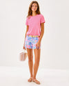 Smiling model in the Lilly Pulitzer Callahan Stretch Short - Elephant Splash. Light blue shorts with pink, blue, yellow, and purple details 