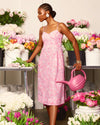 Model in the Lilly Pulitzer Allarie Midi Dress - Rousseau Pink - Tulip To Tango holding a watering can in front of tables of flowers 