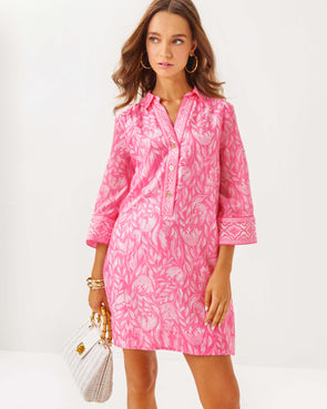 Model in the Lilly Pulitzer Daphnie Tunic Dress - Rousseau Pink - Tulip To Tango Enginee. A 3/4 sleeve mini dress with a collar and v neck with button closure 
