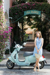Model sitting ojn the back of a vespa in Italy wearing the Duffield Lane Lina Dress - Blue Sky & White Stripe