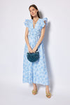 Woman wearing a blue floral dress holding a blue handbag against a white background