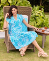 Outdoor model sitting in a chair in the Jude Connally Libby Dress - Enchanted Sea Aqua