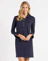 Model in the Jude Connally Midge Dress - Navy/Gold. A navy dress with gold buttons down the front, a shirt style collar, and split arm hems