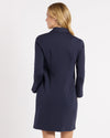 Back view of model in the Jude Connally Midge Dress - Navy/Gold. A navy dress with gold buttons down the front, a shirt style collar, and split arm hems,