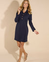 Smiling model in the Jude Connally Midge Dress - Navy/Gold. A navy dress with gold buttons down the front, a shirt style collar, and split arm hems,