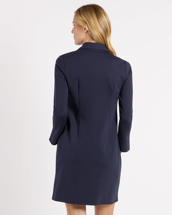 Back view of model in the Jude Connally Midge Dress - Navy/Gold. A navy dress with gold buttons down the front, a shirt style collar, and split arm hems,