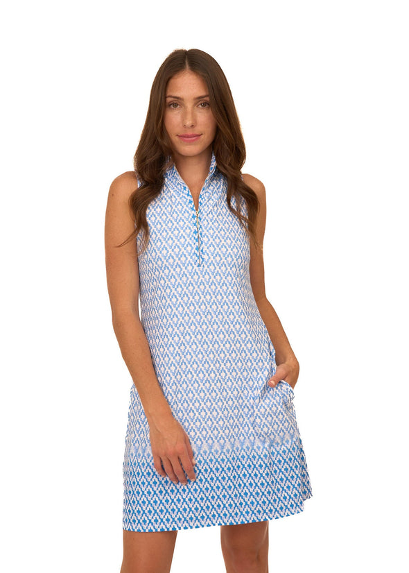 Model in the Cabana Life Seaside 1/4 Zip Sleeveless Sport Dress. A sleeveless, 1/4 zip neckline, mini dress with pockets with a blue and white geometric pattern 