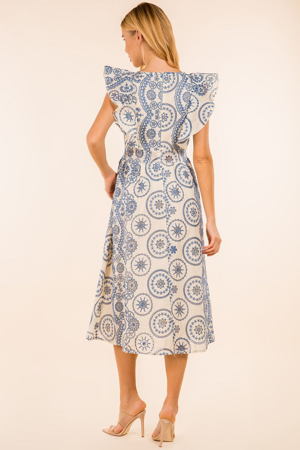 Back view of the model in the Providence Eyelet Midi Dress. A midi length dress with blue eyelet detailing, with puffy sleeves and a zip closure