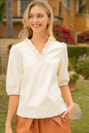 Blonde model wearing ruffle v-neck 3/4 sleeves vegan leather top in cream
