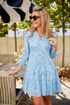 Model outside in a blue floral mini dress with a v neck and long sleeves 