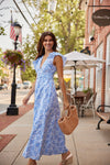 Woman in a blue dress walking on a sidewalk with a casual atmosphere.