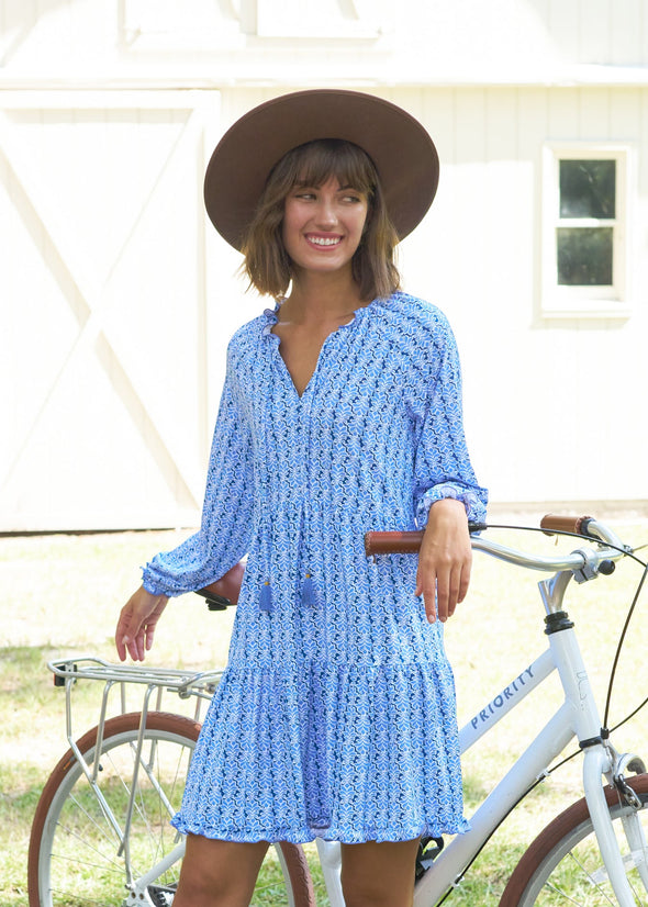 Model leaning against a bike in the Cabana Life Sullivans Island Tiered Ruffle Dress