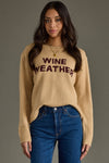 Woman wearing a beige sweater with 'Wine Weather' text against a gray background