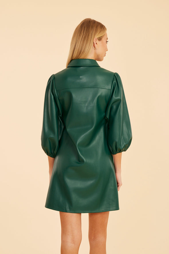 Back view of the model wearing the Dolce Cabo Soft Vegan Leather Dress in Forest Green. A mini shift silhouette with soft faux leather, 3/4 puff sleeves, and front button detailing