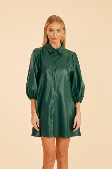 Model is wearing the Dolce Cabo Soft Vegan Leather Dress in Forest Green. A mini shift silhouette with soft faux leather, 3/4 puff sleeves, and front button detailing