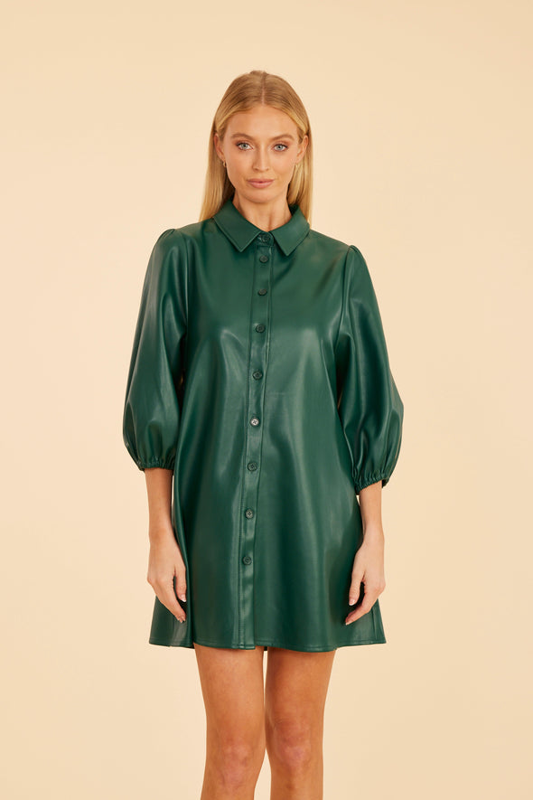 Model is wearing the Dolce Cabo Soft Vegan Leather Dress in Forest Green. A mini shift silhouette with soft faux leather, 3/4 puff sleeves, and front button detailing