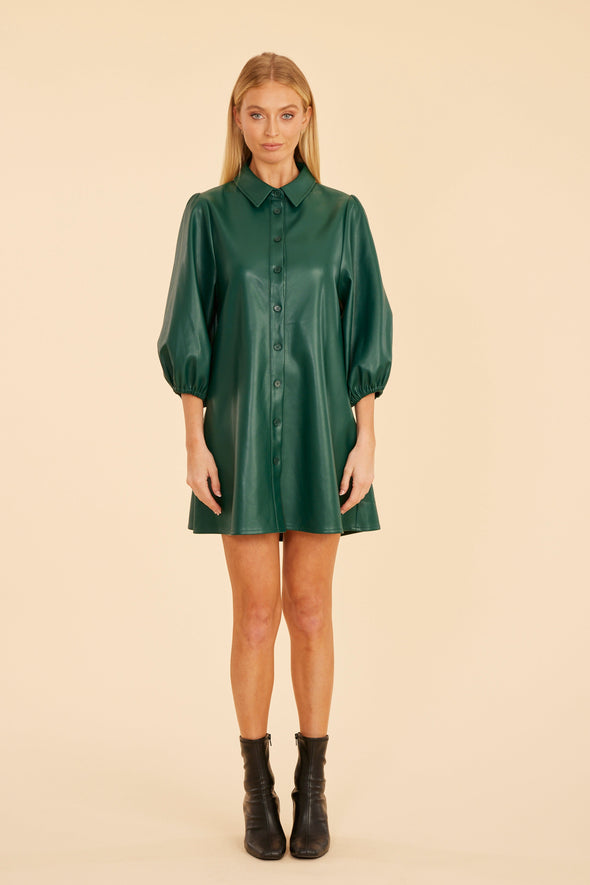 Model is wearing the Dolce Cabo Soft Vegan Leather Dress in Forest Green. A mini shift silhouette with soft faux leather, 3/4 puff sleeves, and front button detailing