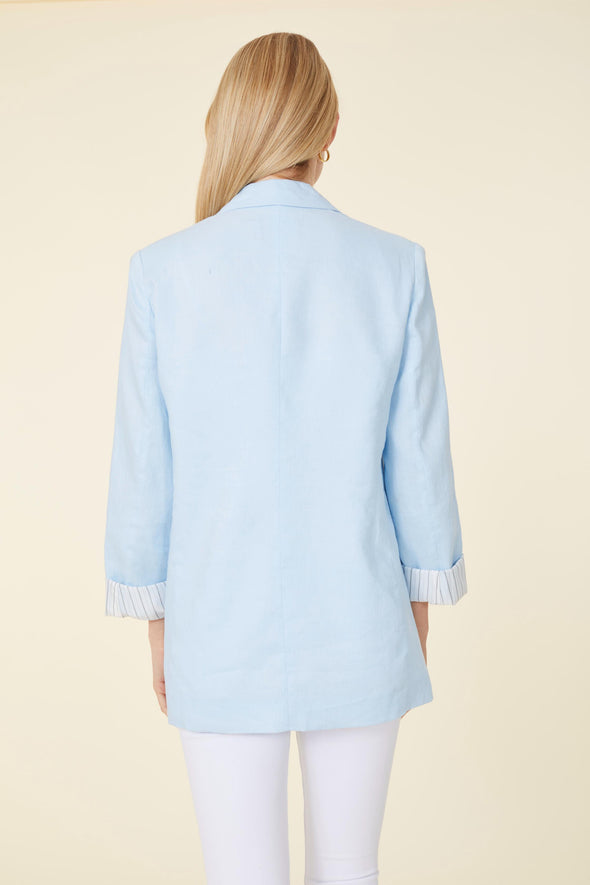 Back view of model in a light blue linen blazer. Stripped lining that shows when cuffed