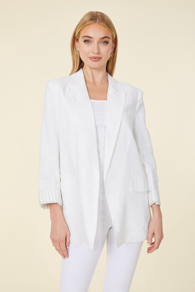 Model in a white linen blazer with light stripes on cuff with white pants 