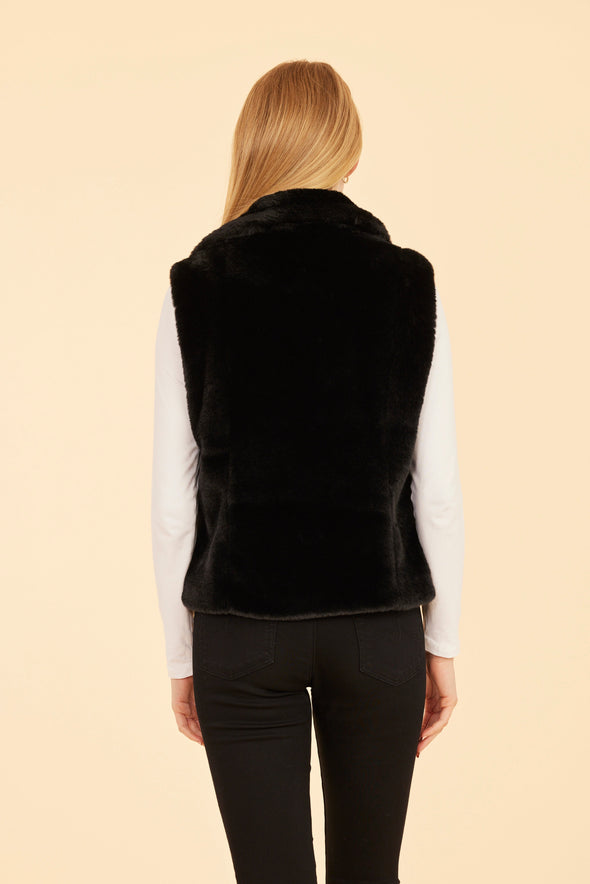 Back view of model wearing the Dolce Cabo Faux Fur Vest in Black, featuring a cozy fold-over collar and pockets