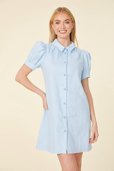 Model in a short light blue dress, with a collar, buttons down the front, and puff sleeves