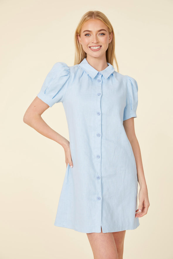 Model in a short light blue dress, with a collar, buttons down the front, and puff sleeves