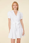 Smiling model in a short white dress with a collar, buttons down the front, puff sleeves, and a belt