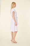 Side view of model in a knee length pink seersucker dress with a collar, pockets on the chest, and a tie belt. The Dolce Cabo Grace Dress