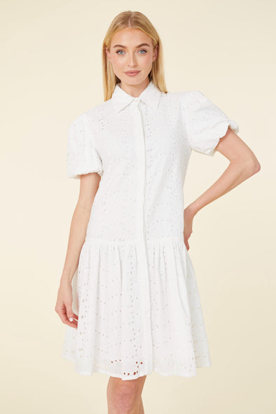 Model in a white eyelet short dress with a collar, buttons, and puff sleeves