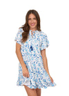 Smiling model  in the Cabana Life Bubbly Short Sleeve Tiered Ruffle Dress. A short sleeved, tiered, v-neck dress that is white with blue floral pattern 