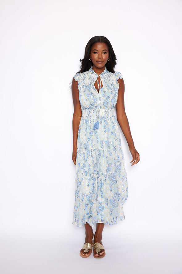 Model in a tiered midi dress with a ruched waist, flutter sleeves, and v neck. It has a beautiful blue, purple, metallic gold floral print, that is both subtle and stunning