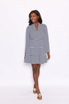 Smiling model wearing a mini length, long sleeved, tiered dress with navy and white stripes. She is also wearing gold sandals