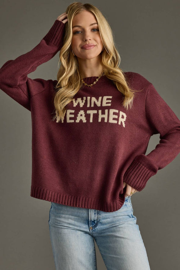 Woman wearing a maroon sweater with 'WINE WEATHER' text against a gray background