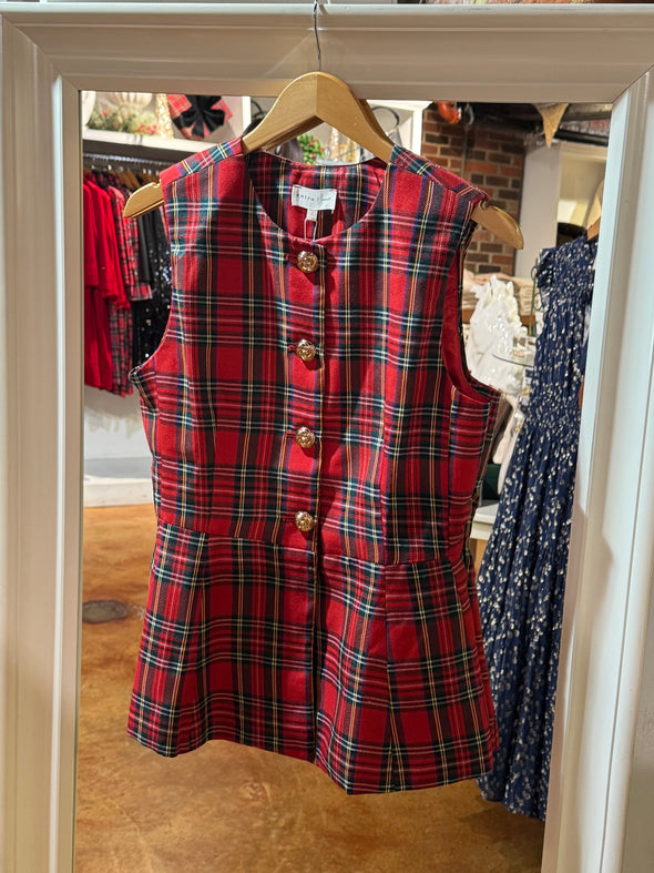 Red plaid sleeveless top on a hanger with a blurred store background