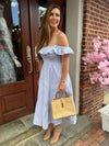 Smiling model outside holding the Chatham Straw Bag - tan. A woven bag with tan trim and a bamboo handle 