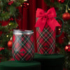 Two plaid tumblers with red bows on a green surface with Christmas tree in the background