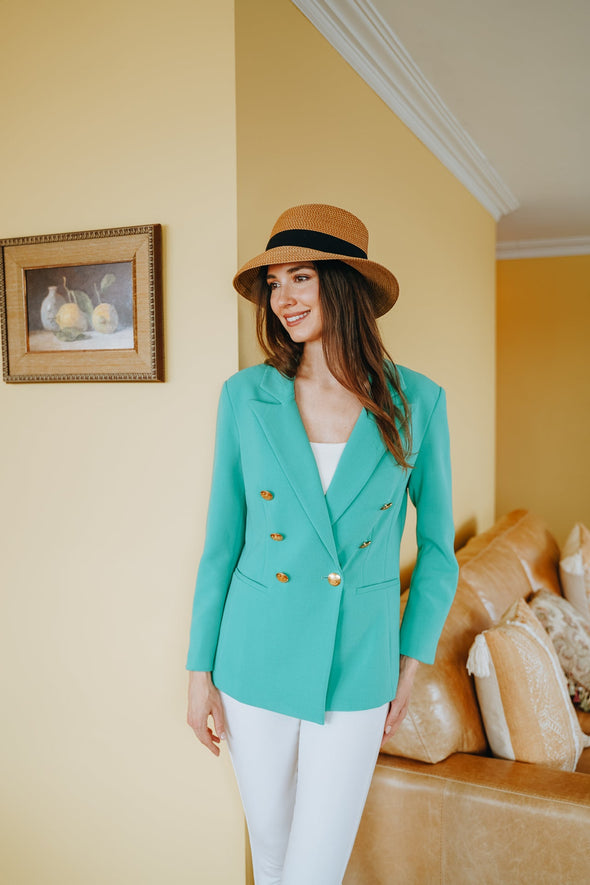 Model in living room in straw hat, white jeans and Patty Kim Bermuda Jacket in Spring Green