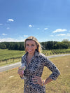 Woman in a black and beige pattern and a tie detail on the front, outside in a vineyard