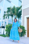 Model in a blue/ aqua patterned tiered maxi dress, with touches of green and white and other shades of blue 