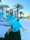 Side View of Model Seated by Pool Wearing Teal Maxi Dress with Tiered skirt and 3/4 Sleeves