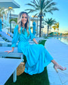 Side View of Model Seated by Pool Wearing Teal Maxi Dress with Tiered skirt and 3/4 Sleeves